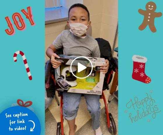 A little boy in a wheelchair holding a holiday gift he received