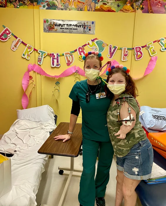 A patient with an external fixator on her arm smiling with her physical therapist