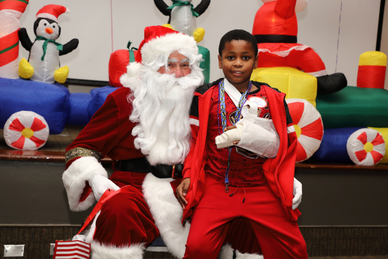 Boy with arm in a sling smiling on Santa’s lap