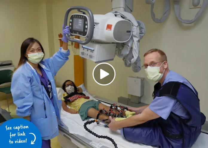 Two staff members readying a patient lying down waiting for X-ray images to be taken