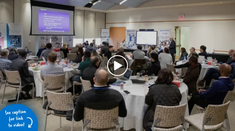 Room full of doctors sitting at tables looking at a PowerPoint presentation on a projection screen