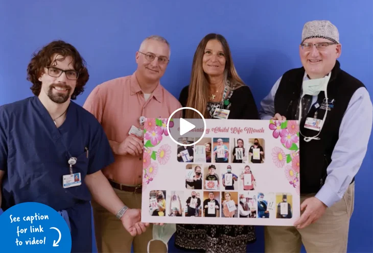 Photo of Pediatric Liaison Marilyn Richardson smiling holding up a thank you sign with our three pediatric surgeons