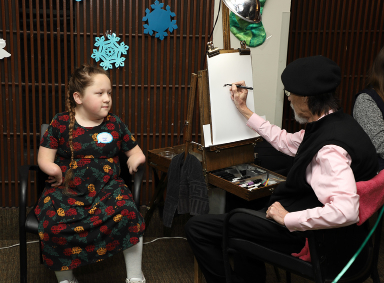 Girl having her caricature drawn by an artist in a beret