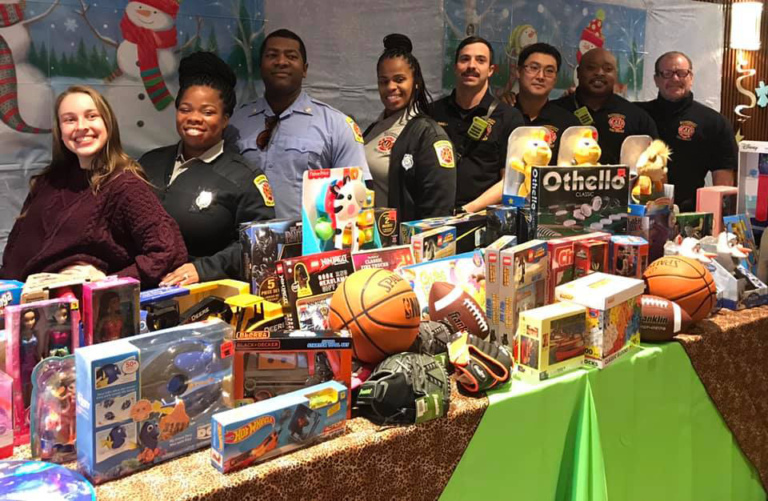 Baltimore City Fire Department staff smiling behind the table of toys they donated for patient families
