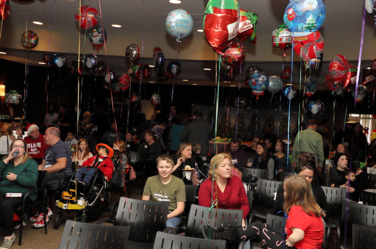 Families sitting in chairs decorated with balloons enjoying the International Center for Limb Lengthening pediatric holiday party