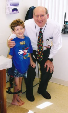 Christopher as young boy wearing external fixator with Dr. Herzenberg at International Center for Limb Lengthening