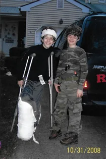 Christopher as a boy on crutches wearing external fixator covered in bandages as part of military Halloween costume with his twin