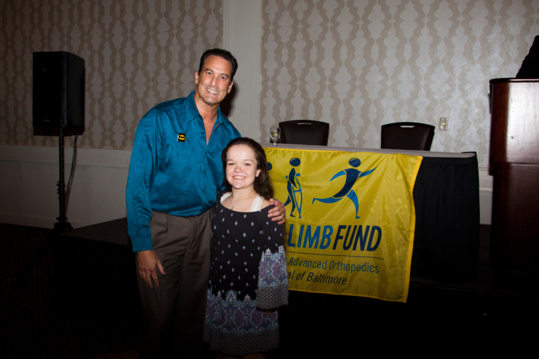 Family member of Leonard B. “Batman” Robinson with female patient in front of Save-A-Limb Fund banner at Rubin Institute for Advanced Orthopedics 2017 Save-A-Limb Fund Dinner