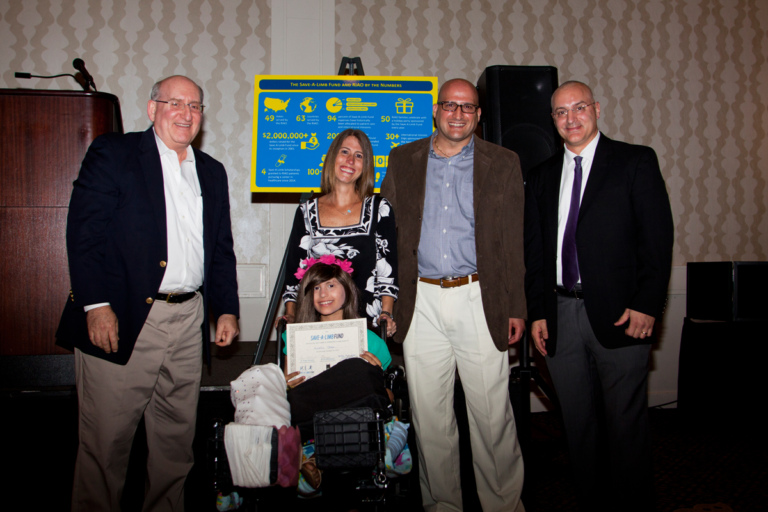 Dr. John Herzenberg and Dr. Shawn Standard present an award to a young girl in a wheelchair and her parents at Rubin Institute for Advanced Orthopedics 2017 Save-A-Limb Fund Dinner
