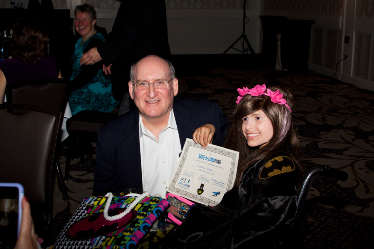 Dr. John Herzenberg with young girl in wheelchair with award at Rubin Institute for Advanced Orthopedics 2017 Save-A-Limb Fund Dinner