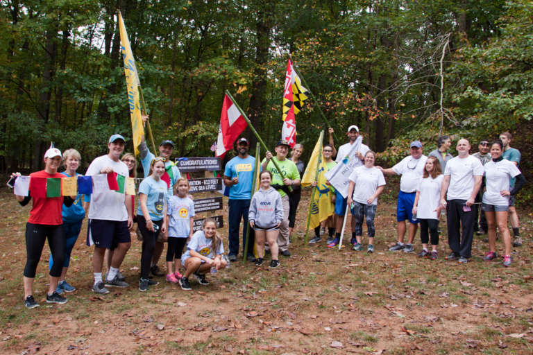 Earl Cole, the winner of Survivor: Fiji reality television show and founder of Perthes Kids Foundation, Dr. Shawn Standard and Dr. John Herzenberg pose with participants of the hike challenge at the top of the summit with flags Rubin Institute for Advanced Orthopedics 2017 Save-A-Limb Fund Event