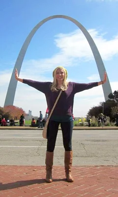 Carly as a young woman with her arms outstretched under St. Louis' Gateway Arch during internal lengthening
