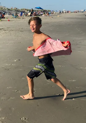 Jeffrey at 10 running on the beach with a towel
