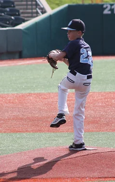 Jeffrey at 11 in baseball uniform winding up for a pitch on a baseball field's pitcher mound