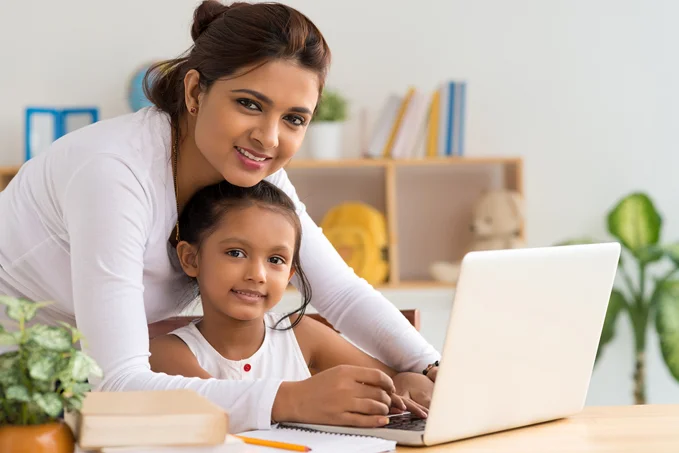Woman and child smiling while using a laptop