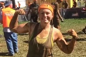 Carly wearing muddy clothes and showing off her muscles at Tough Mudder