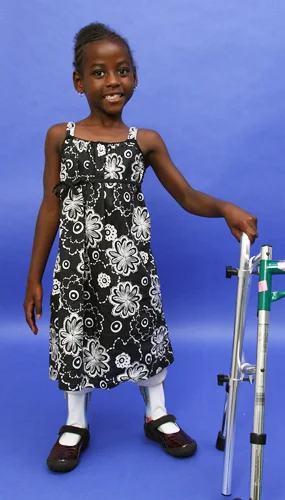 Melissa standing with leg braces and walker