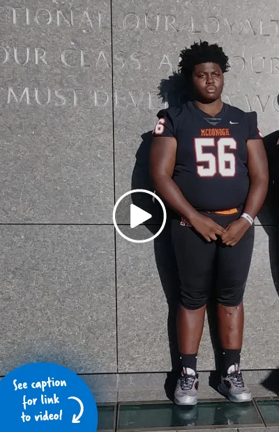 Tamarus standing with straight legs in his football uniform