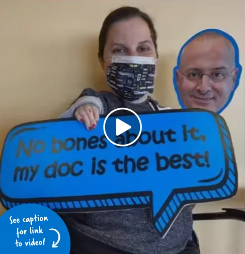 A woman holding a photo of Dr. Shawn Standard and a sign that says “No bones about it, my doc is the best!”