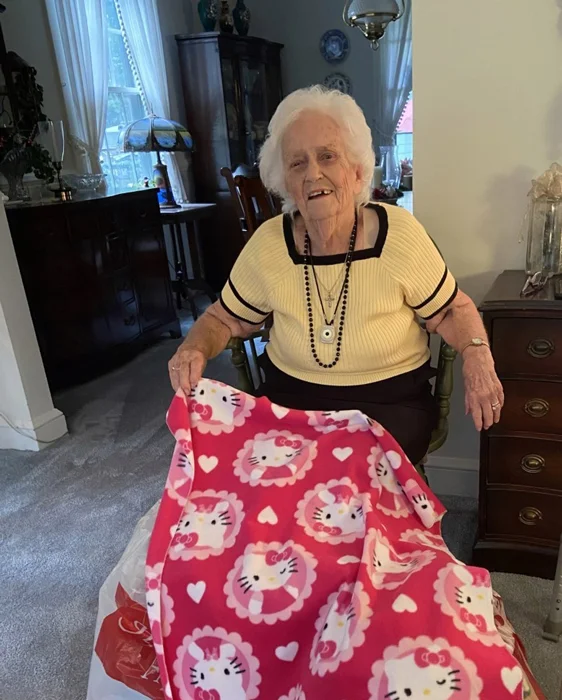 Lillian Warnken sitting with one of the hundreds of blankets she has sewn for pediatric patients