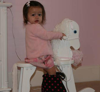 Aria as a young child riding a rocking horse while wearing an external fixator
