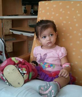 Aria as a young child sitting with an external fixator on her leg