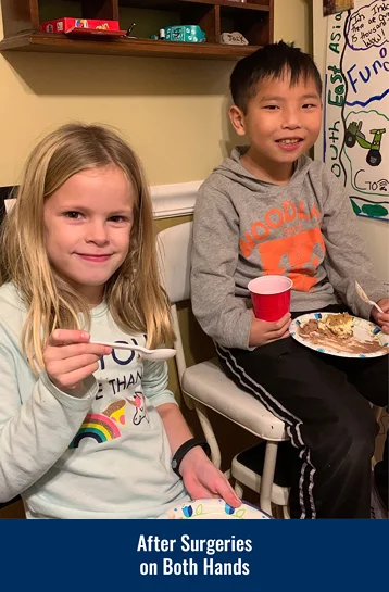 James after surgeries on both hands eating with his cousin; he is holding a fork in one hand and a cup in the other.