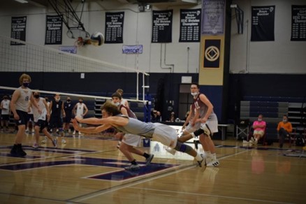 Josh diving for a volleyball in a gym