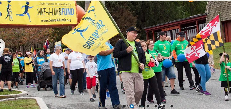 Dr. John Herzenberg holding a Save-A-Limb Fund flag leading participants in the Family Fun Walk